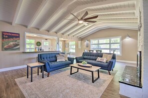 A spacious living room with two dark blue sofas, a wooden coffee table, and a ceiling fan. - Dock! Waterfront Family Home on Lake of the Ozarks (Lake Ozark)