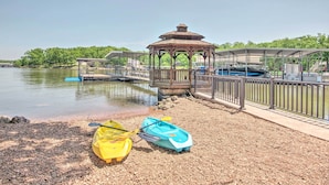 A gazebo near a lake with kayaks and a covered area.