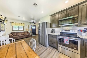 Una cocina moderna con electrodomésticos de acero inoxidable, armarios de madera y un comedor con mesa y sillas de madera.