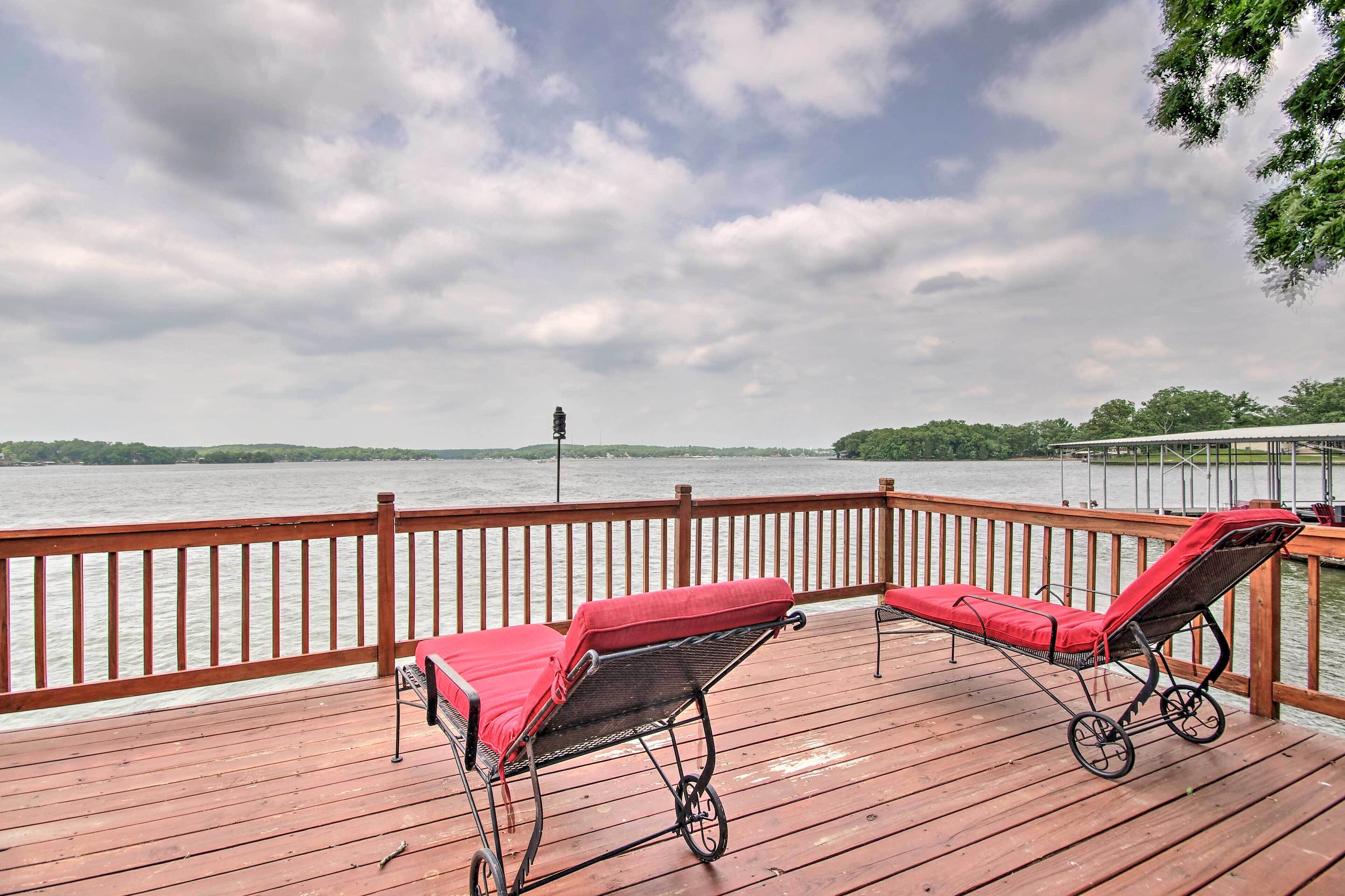 A wooden deck with two sun loungers and a view of a lake.