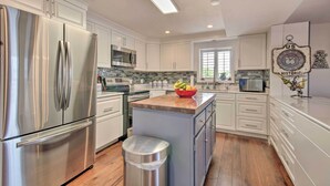 A modern kitchen with stainless steel appliances, white cabinetry, and a central island with a fruit bowl. - Hot Tub, Dock! Waterfront Lake Ozark Home! (Lake Ozark)