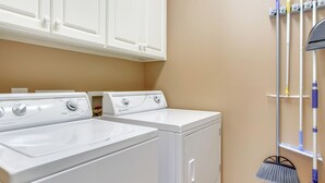 A laundry room with two white front-loading washers and dryers, a wall-mounted drying rack, and a broom. - Lakefront Mccormick Gem: Deck & Golf Course Views (McCormick)