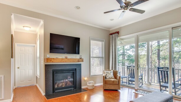 A living room with hardwood floors, a fireplace, a flat-screen TV, and a sliding glass door leading to a deck. - Lakefront Mccormick Gem: Deck & Golf Course Views (McCormick)