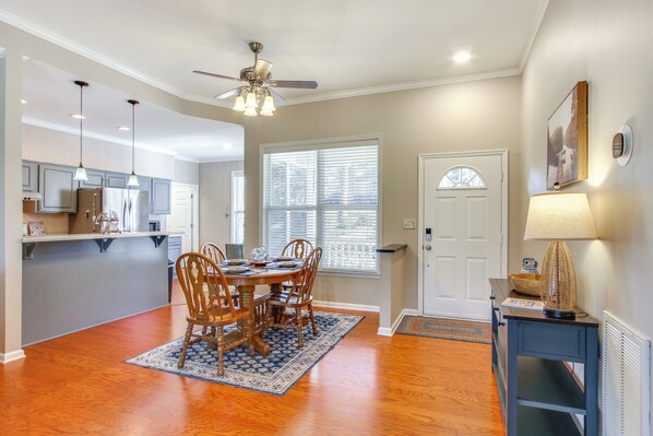 A dining area with a wooden table and chairs, a ceiling fan, and a window with blinds. - Lakefront Mccormick Gem: Deck & Golf Course Views (McCormick)