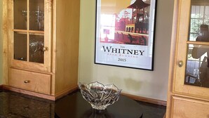 A kitchen with wooden cabinets, a framed picture of a race course, and a crystal bowl on the counter.