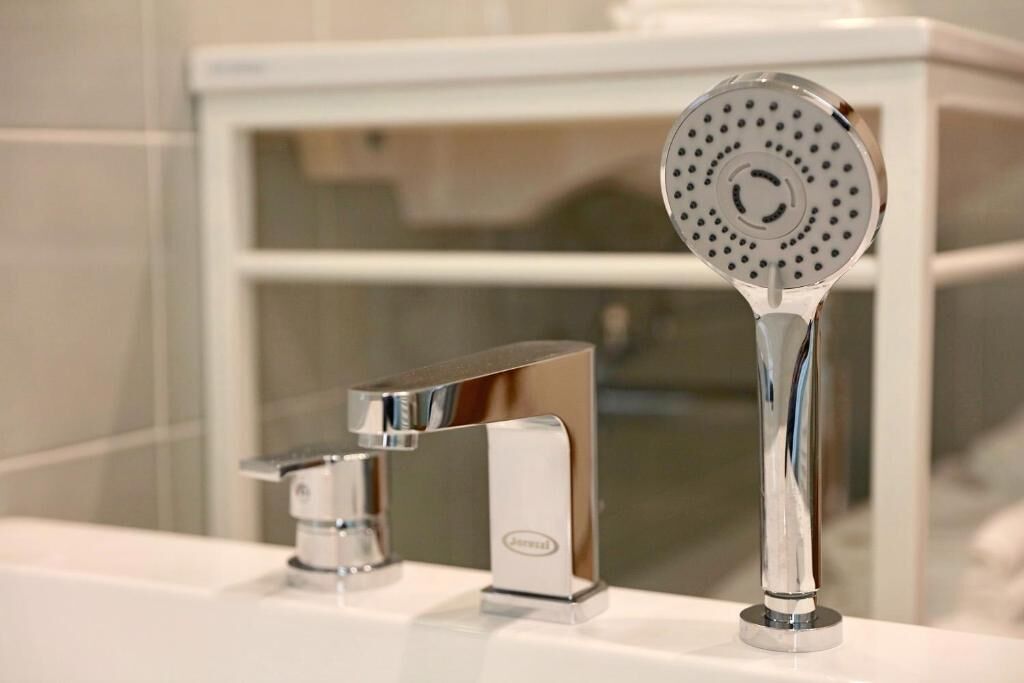 A modern bathroom with a chrome faucet and showerhead.