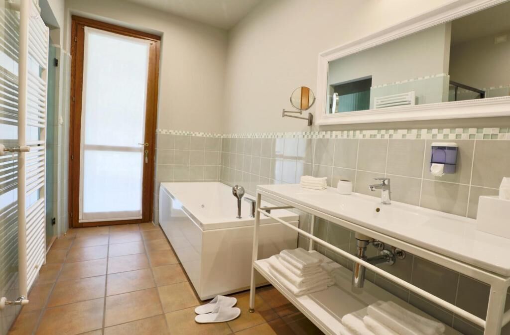 Une salle de bain moderne avec une baignoire, un grand miroir et un meuble-lavabo doté d’un évier et d’un porte-serviettes.