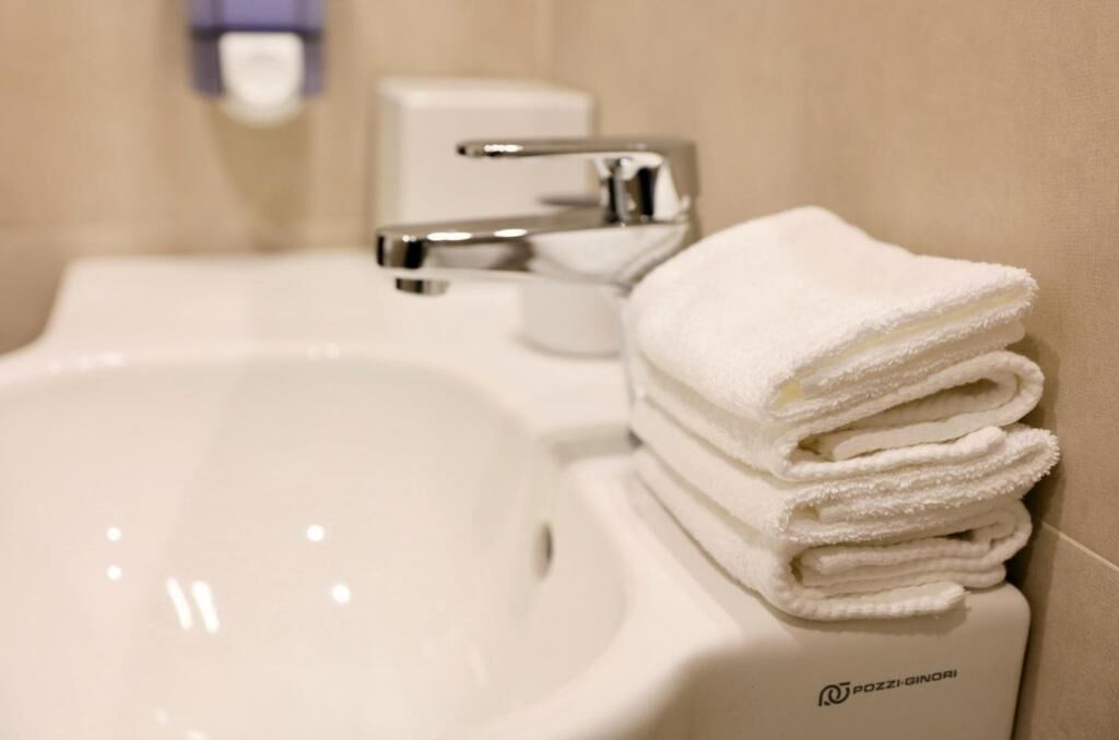 A bathroom sink with a stack of white towels and a soap dispenser.