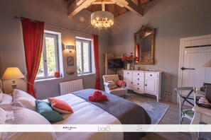 Een slaapkamer met een bed, een kaptafel, een stoel, een spiegel en een kroonluchter.