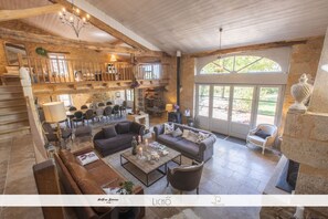 A spacious living area with a high ceiling, wooden beams, and a balcony overlooking a garden. - Maison des Quatre Saisons (Les Esseintes)