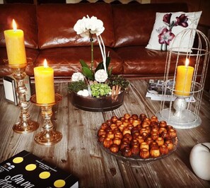 Een houten tafel met kaarsen, een bloemstuk en een bord met kandijfruit.