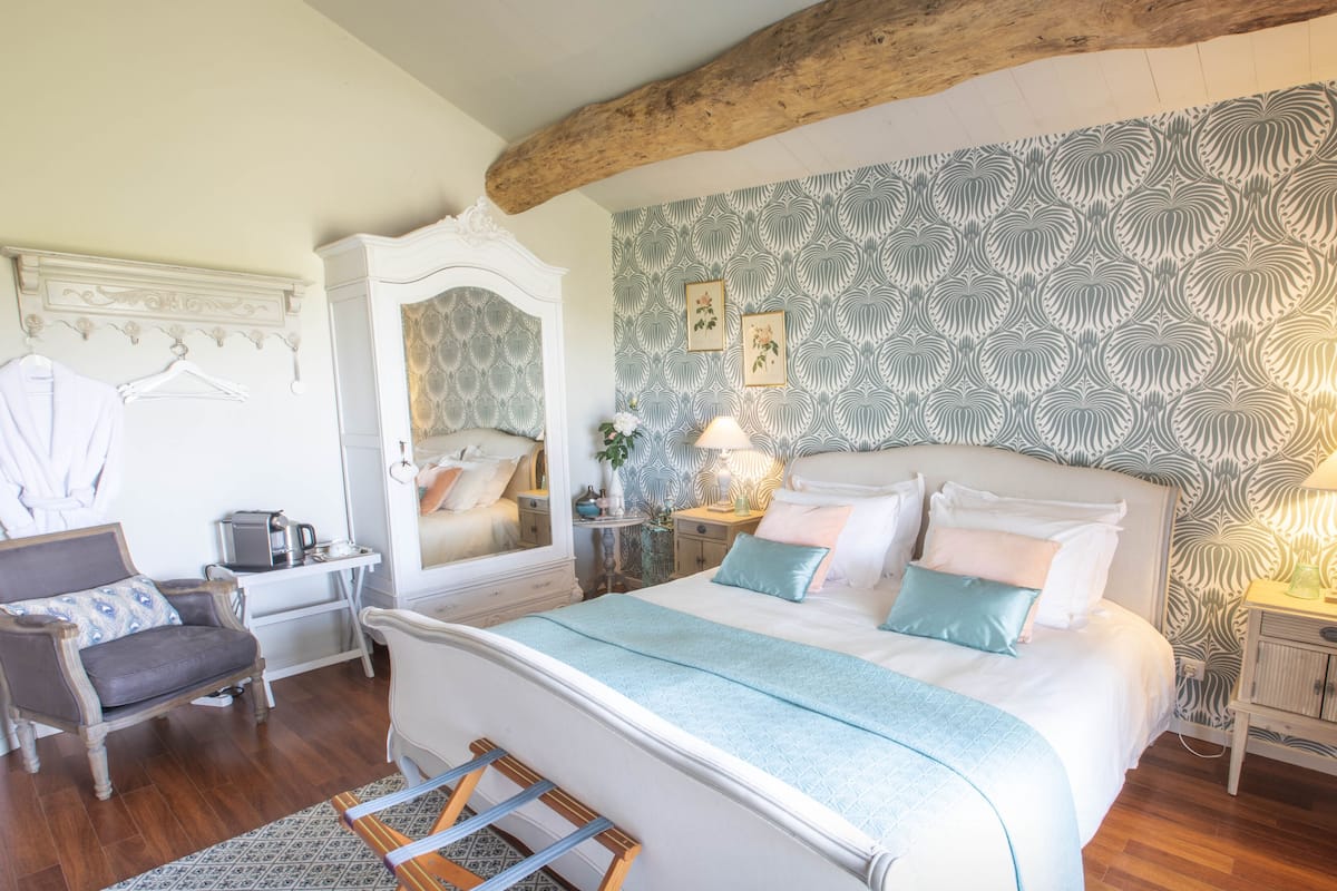 Une chambre à coucher avec un grand lit, une coiffeuse avec un miroir, une chaise et une table de chevet avec une lampe.
