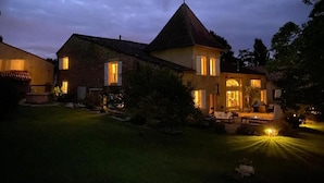 A two-story house with a well-lit front porch and a lawn. - Maison des Quatre Saisons (Les Esseintes)