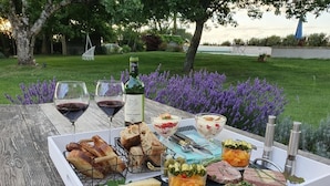 A picnic setup with various foods and drinks on a wooden table in a garden. - Maison des Quatre Saisons (Les Esseintes)