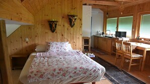A wooden cabin bedroom with a bed, a desk, and a chair.