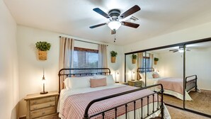 A bedroom with a bed, bedside tables, a ceiling fan, and a large mirror. - Yuma Vacation Rental w/ Private Pool & Patio! (Yuma)