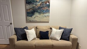 Ein beiges Sofa mit vier Kissen vor einer Tür und einem Bild an der Wand.