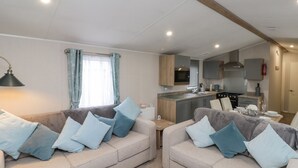 A modern RV interior with two sofas, a kitchen area, and a dining table. - Rowan Court 2 (Scarborough)