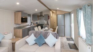 A compact, modern RV interior with a kitchenette, a dining area, and a living space. - Rowan Court 2 (Scarborough)