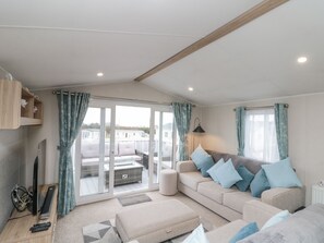 A modern living room with a sofa, ottoman, and a television on a wooden stand. - Rowan Court 2 (Scarborough)