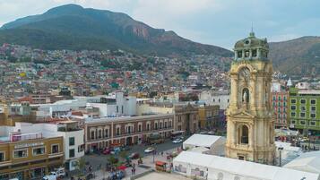 Un pueblo histórico con una imponente torre del reloj, una calle animada y montañas al fondo.