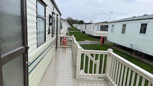 A row of mobile homes with a wooden deck and white railings. - 2 Bedroom Caravan Hunstanton Pets go Free (Hunstanton)