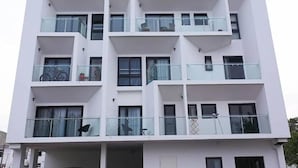 Un immeuble résidentiel à plusieurs étages, doté de balcons, de grandes fenêtres et d’une façade plane.