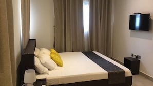 Une chambre d’hôtel équipée d’un lit, d’une télévision, d’une table de chevet et d’un appareil de climatisation.
