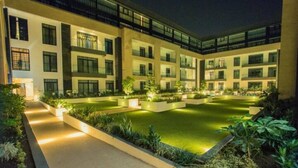 A modern hotel courtyard with a central pool, surrounded by greenery and illuminated pathways. - Cozy Studio Apartment in heart of Cantonment (Accra)