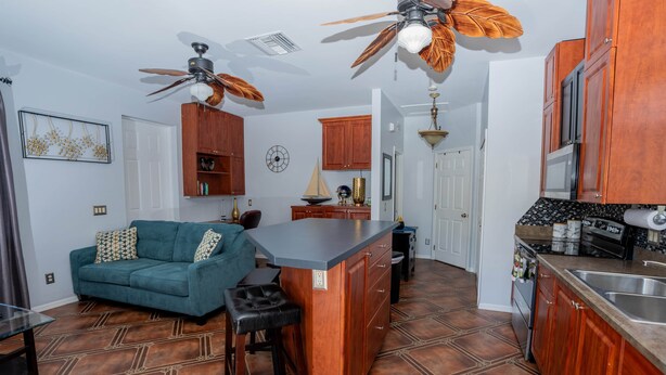 A compact kitchen with a central island, wooden cabinets, and a ceiling fan. - Little Cottage on the Field (Buckingham)