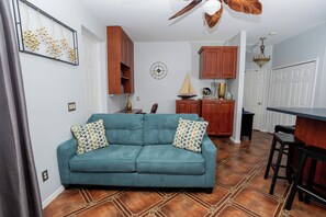 A living room with a teal sofa, wooden cabinets, a clock, and a sailboat model. - Little Cottage on the Field (Buckingham)