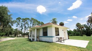 A small, single-story building with a flat roof, a front porch, and a patio area with a table and chairs. - Little Cottage on the Field (Buckingham)