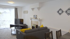 A living room with a sofa, TV, fireplace, and a dining table with chairs.