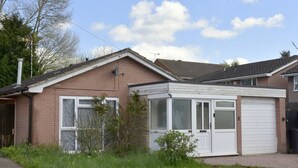 A single-story house with a garage, a small garden, and a clear sky.