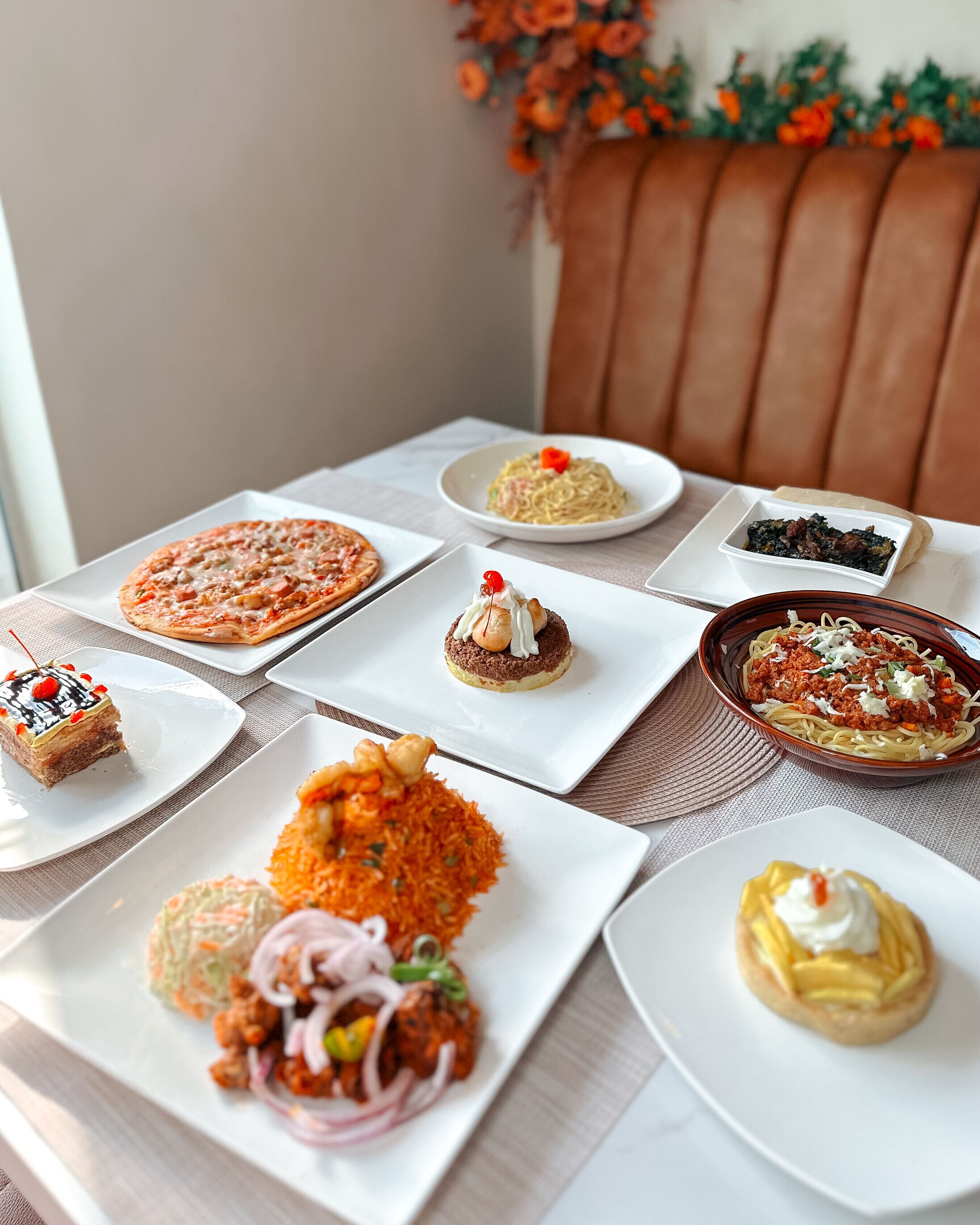 A table with various dishes including pizza, pasta, and desserts.