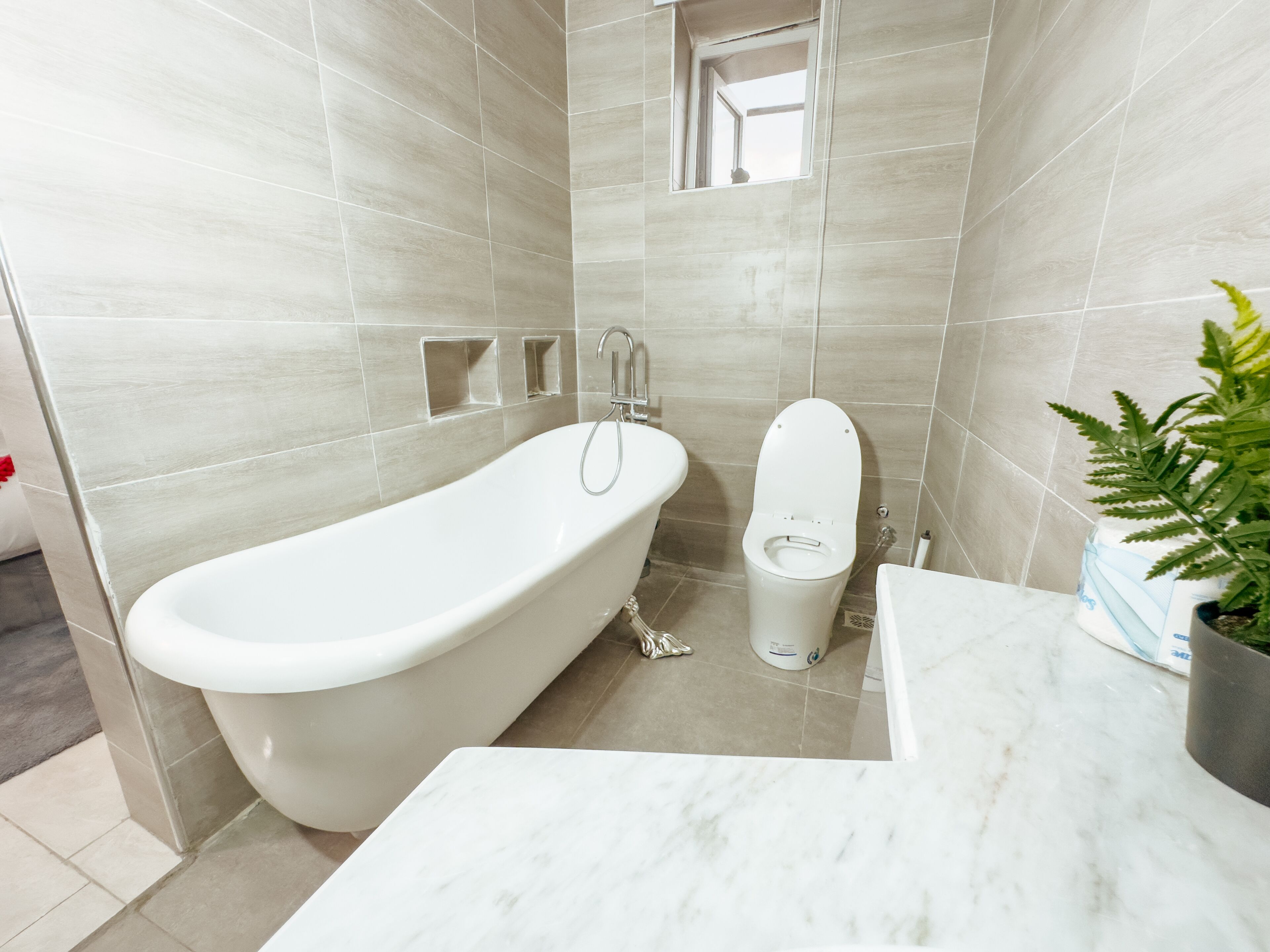 A modern bathroom with a freestanding bathtub, a toilet, and a marble countertop.