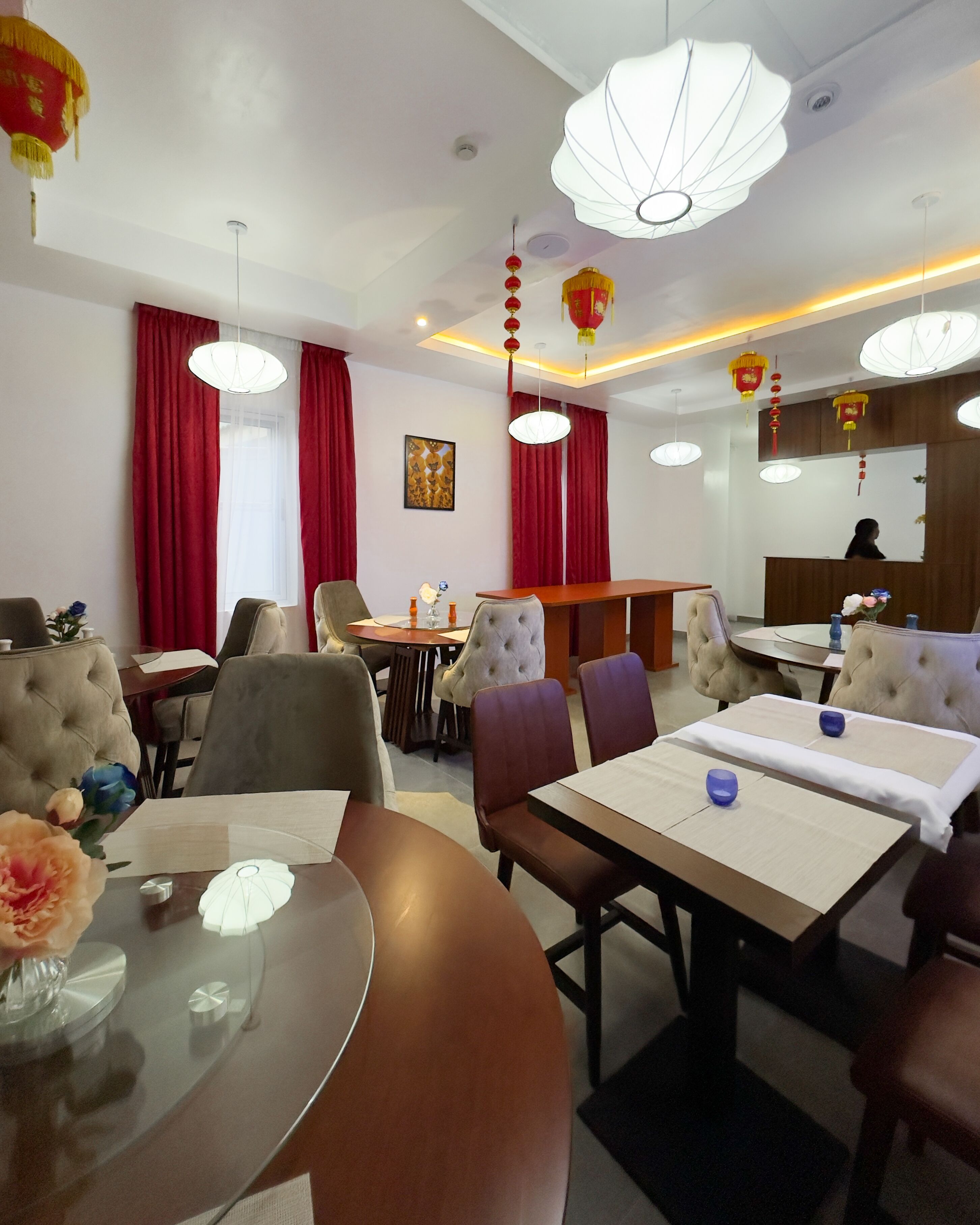 A hotel dining area with round tables, chairs, and hanging lanterns.