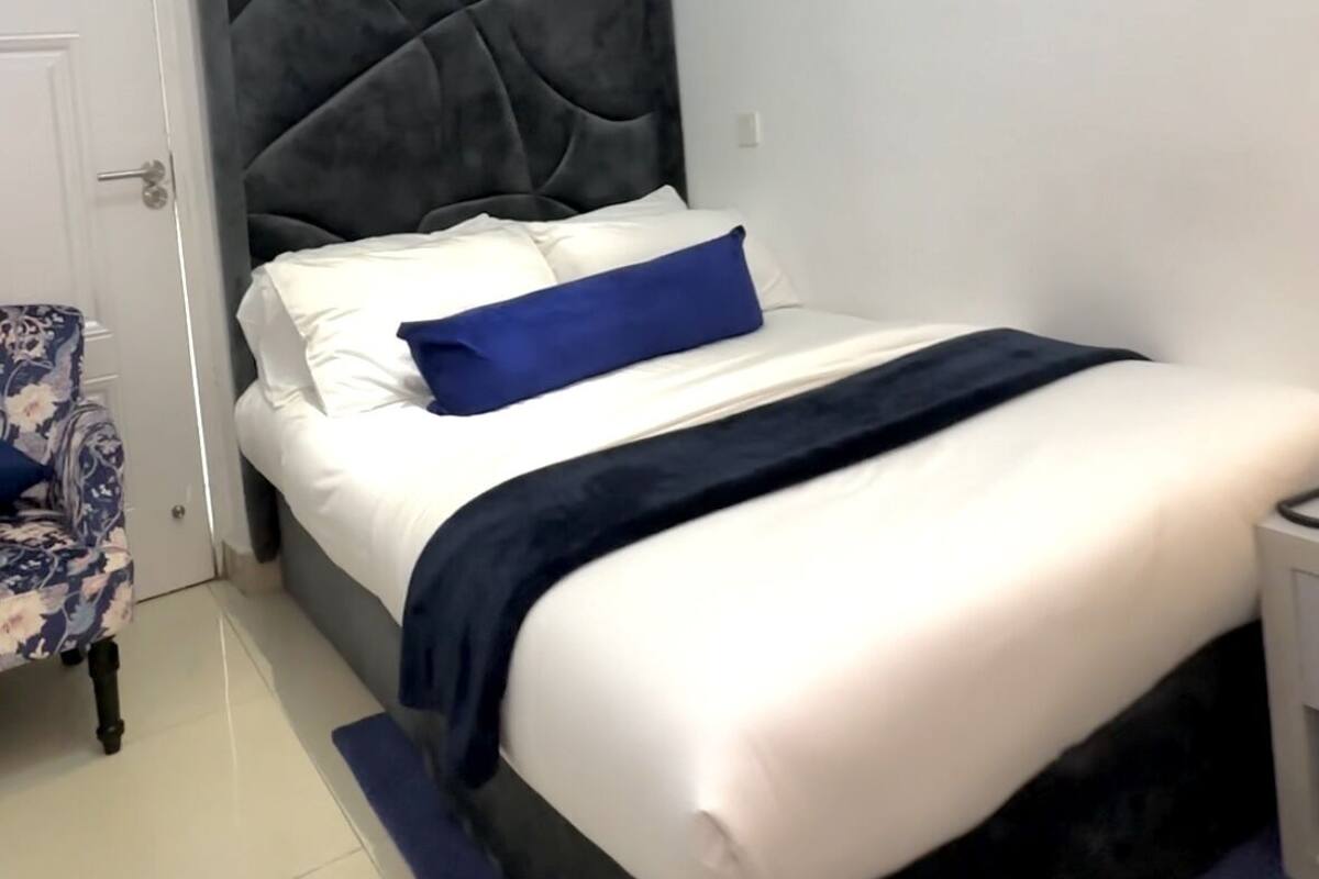 A bedroom with a bed, a chair, and a door.
