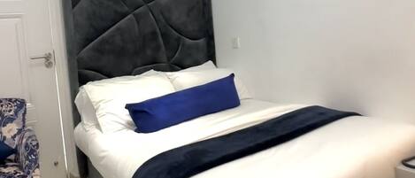 A bedroom with a bed, a chair, and a door.