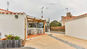 Asuinrakennus, jossa on katettu patio, ulkotila istumiseen ja kivimuuri.