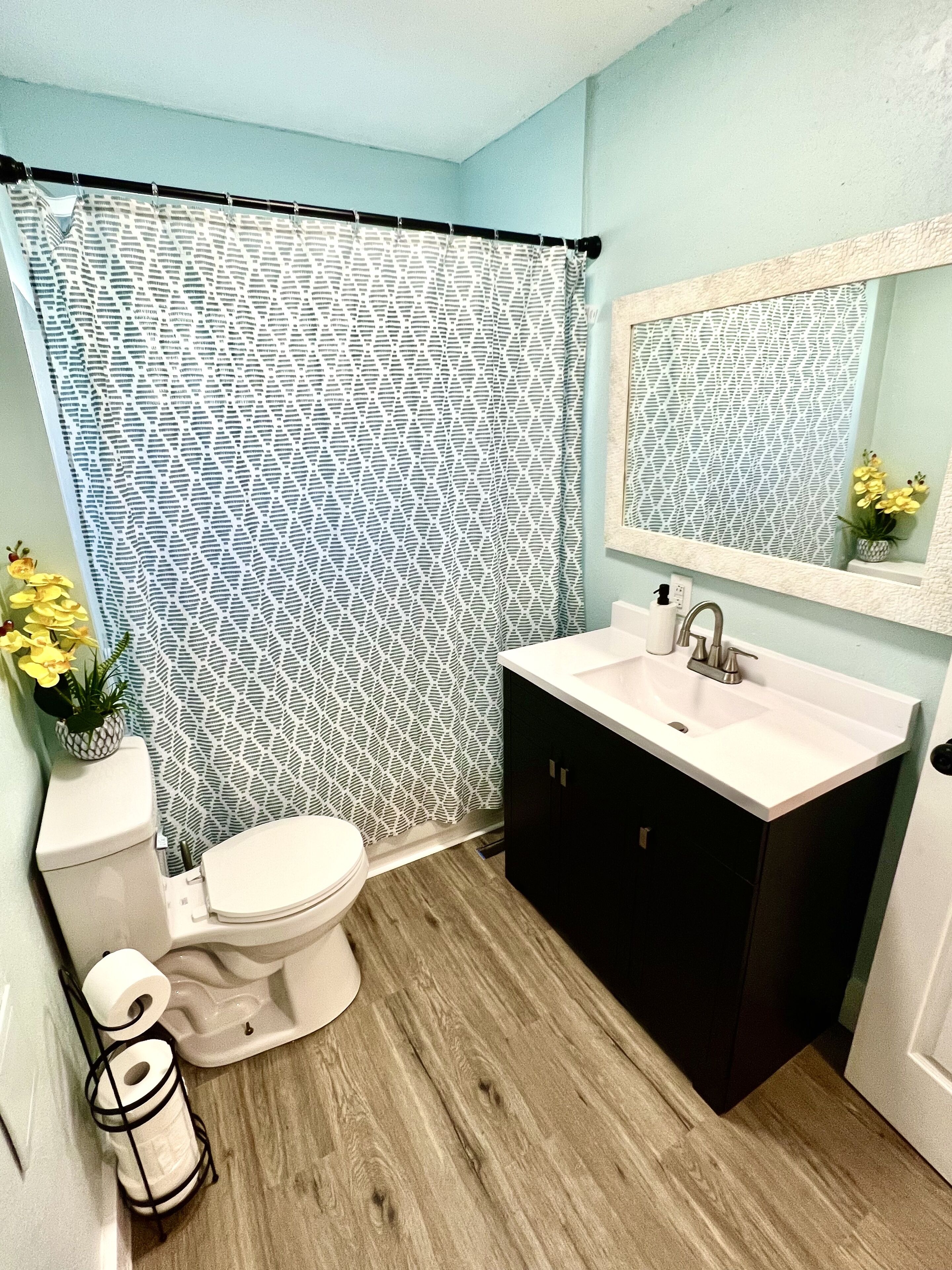 A bathroom with a toilet, sink, and shower curtain.