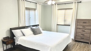 A bedroom with a bed, a nightstand, a dresser, and a ceiling fan.