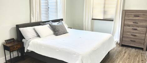 Ein Schlafzimmer mit Bett, Nachttisch, Schminktisch und Deckenventilator.