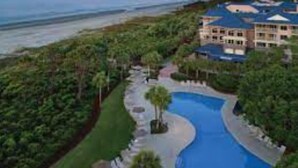 Ein Resort mit großem Pool, Blick auf den Strand und mehreren Gebäuden.