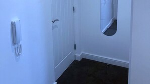A narrow hallway with a white door, a telephone, and a mirror on the wall. - Captivating 1-bed Apartment in Nottingham (Nottingham)