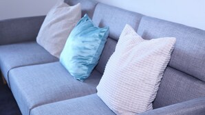 A grey sofa with three pillows in different textures and colors. - Captivating 1-bed Apartment in Nottingham (Nottingham)