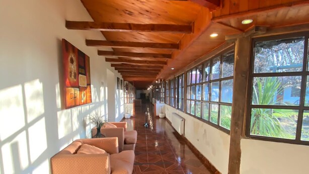 Un pasillo con techo de madera, suelo estampado y una fila de sofás a lo largo de una pared.