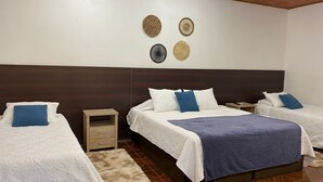 Habitación de hotel con dos camas, cabecero de madera, mesita de noche pequeña y un adorno en la pared.
