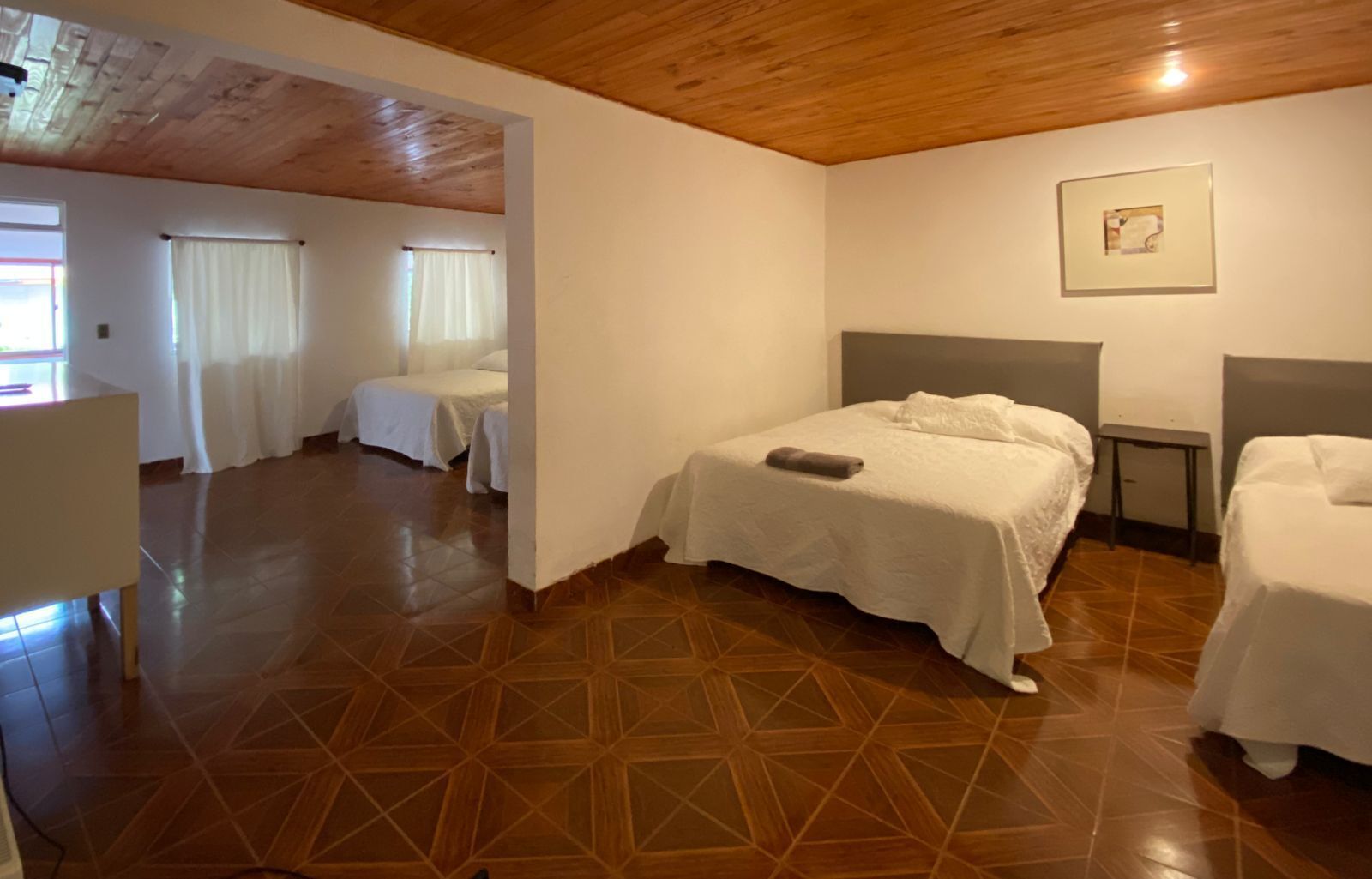 Habitación de hotel con una cama grande, un escritorio y una silla. Hay dos ventanas con cortinas.