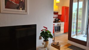 Ein Wohnzimmer mit Fernseher, Topfpflanze und einem kleinen Tisch mit Kerzen.